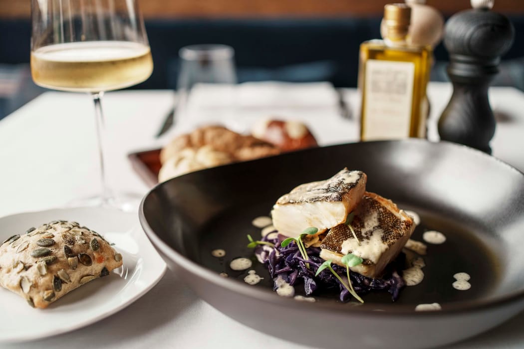 Dettaglio secondo piatto di pesce e calice di vino