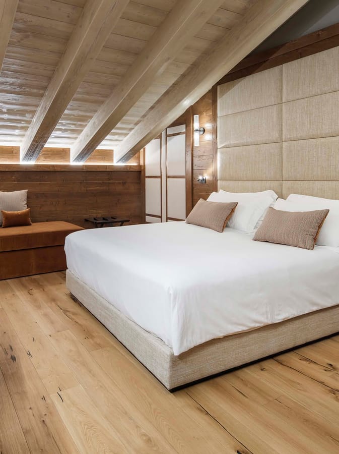 Dettaglio letto matrimoniale e soffitto con travi a vista Deluxe Tripla