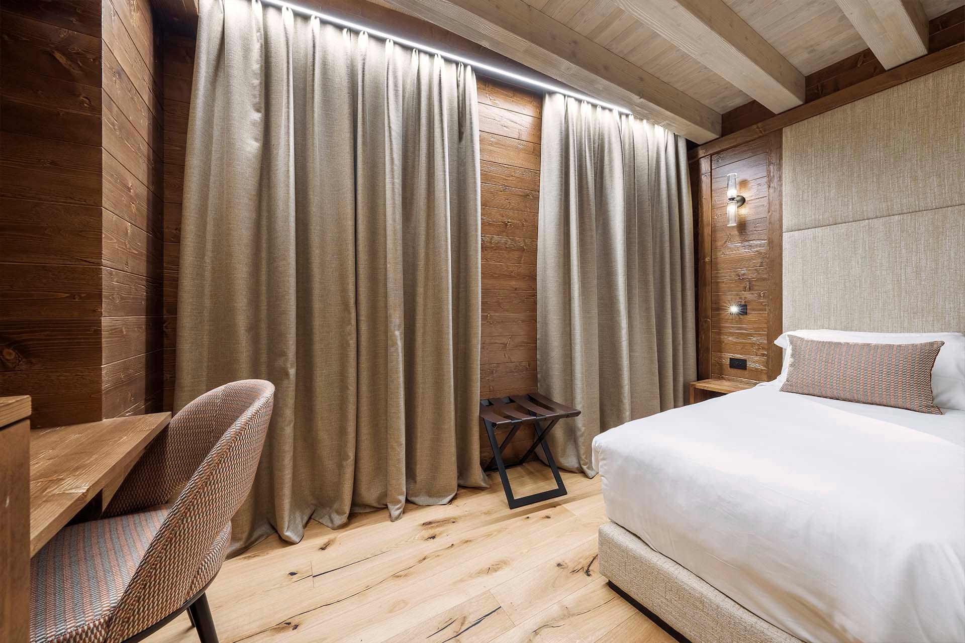 Dettaglio letto matrimoniale, scrivania e poggia valigia Camera Family Casa Guargnè